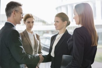 Confident business people shaking hands at workplace
