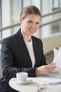Portrait of confident businesswoman with documents sitting at office cafe