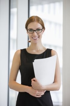 Portrait of confident businesswoman holding documents in office