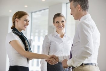 Happy business partners shaking hands in office