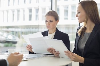 Businesswomen discussing over documents in office cafeteria