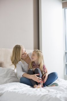 Happy woman and daughter looking at each other in bedroom