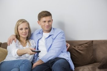 Mid adult couple watching television on sofa