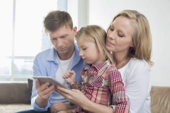 Parents with daughter using digital tablet at home