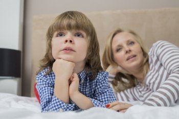 Thoughtful boy with mother in bed