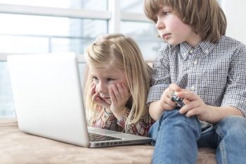 Brother and sister looking at laptop in living room