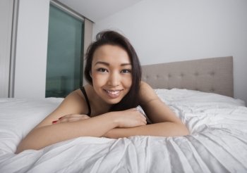 Portrait of happy young woman resting in bed