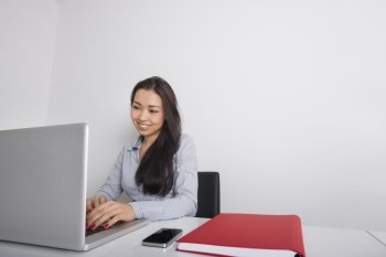 Happy young businesswoman using laptop at office desk