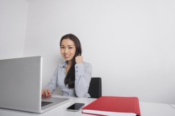 Portrait of happy businesswoman using laptop at office desk