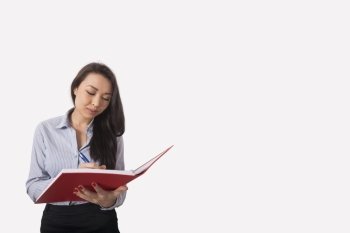 Businesswoman writing in book against gray background