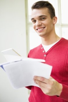 Portrait of confident young businessman with documents in office