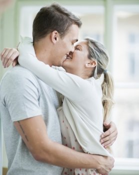 Loving couple kissing while hugging in house