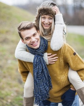 Portrait of happy man piggybacking woman in park