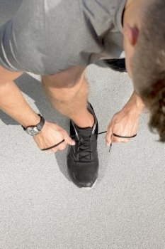 High angle view of sporty man tying shoelace on street