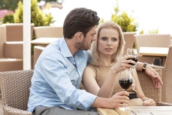 Young couple talking while having red wine at outdoor restaurant
