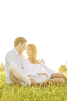 Loving young couple looking at each other on grass against clear sky
