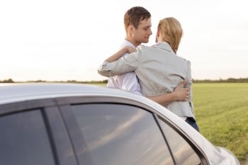 Romantic young couple leaning on car during road trip