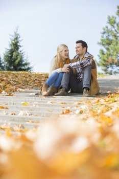 Happy young couple sitting on steps in park