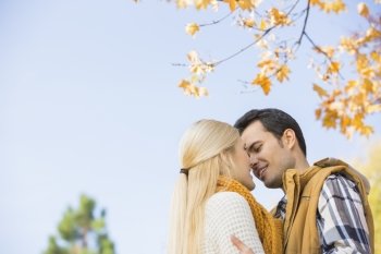 Low angle view of couple kissing against clear sky during autumn