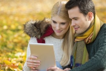 Couple using digital tablet in park during autumn