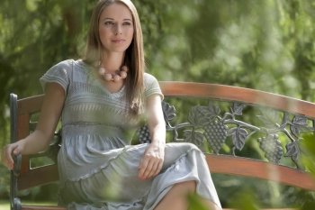 Beautiful young woman sitting on bench in park