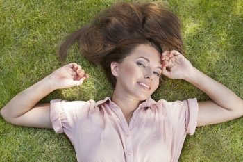 High angle portrait of beautiful young woman lying in grass