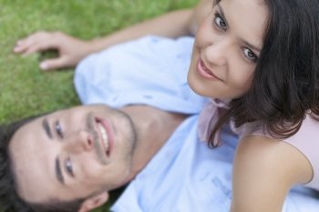 High angle portrait of playful young woman on top of man in park