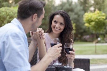 Romantic young couple having red wine in park