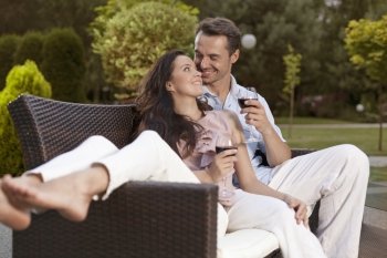 Romantic young holding wine glasses on easy chair in park