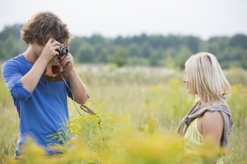 Young man photographing woman in field