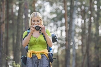 Female hiker photographing through digital camera in forest