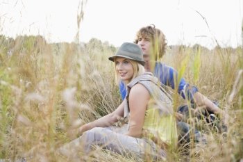 Young couple looking away while relaxing in field