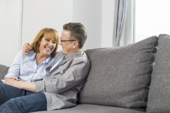 Happy loving couple sitting on sofa at home