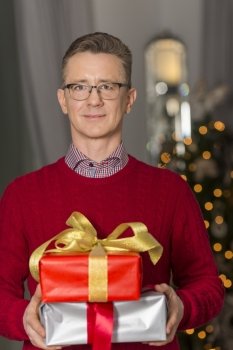 Portrait of mature man holding stack of Christmas presents