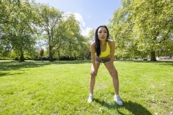 Full length of tired fit woman taking a break while exercising in park