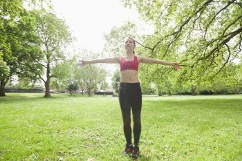 Full length of young woman listening to music while exercising in park