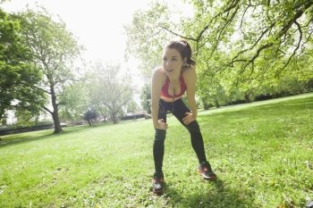 Full length of tired fit woman taking break while exercising in park