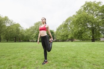 Full length of fit young woman performing stretching exercise in park