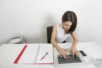 High angle view of businesswoman using laptop at desk in office