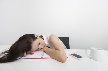 Tired businesswoman sleeping at desk in office