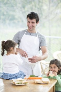 Happy father preparing food with little daughters at home