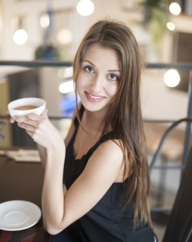 Portrait of smiling young woman having coffee at cafe