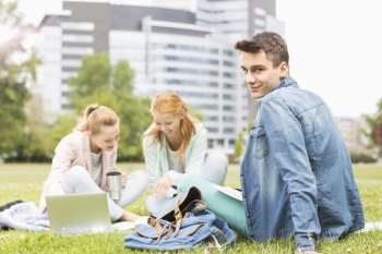 Portrait of young man with female friends studying on university campus