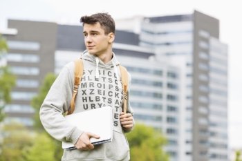 Young male university student holding books at campus