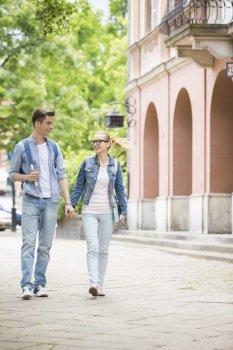 Full length of young college couple talking while walking in campus