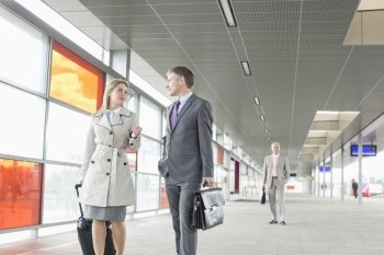Businessman and businesswoman conversing while walking in railroad station