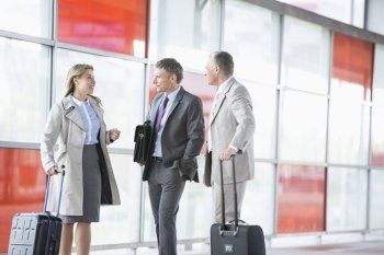 Businesspeople with luggage talking on railroad platform