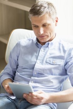 Middle-aged man using digital tablet at home