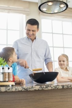Happy man with children preparing food in kitchen