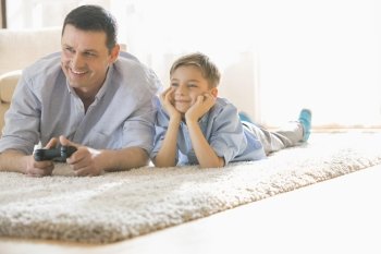 Happy father and son playing video game on floor at home